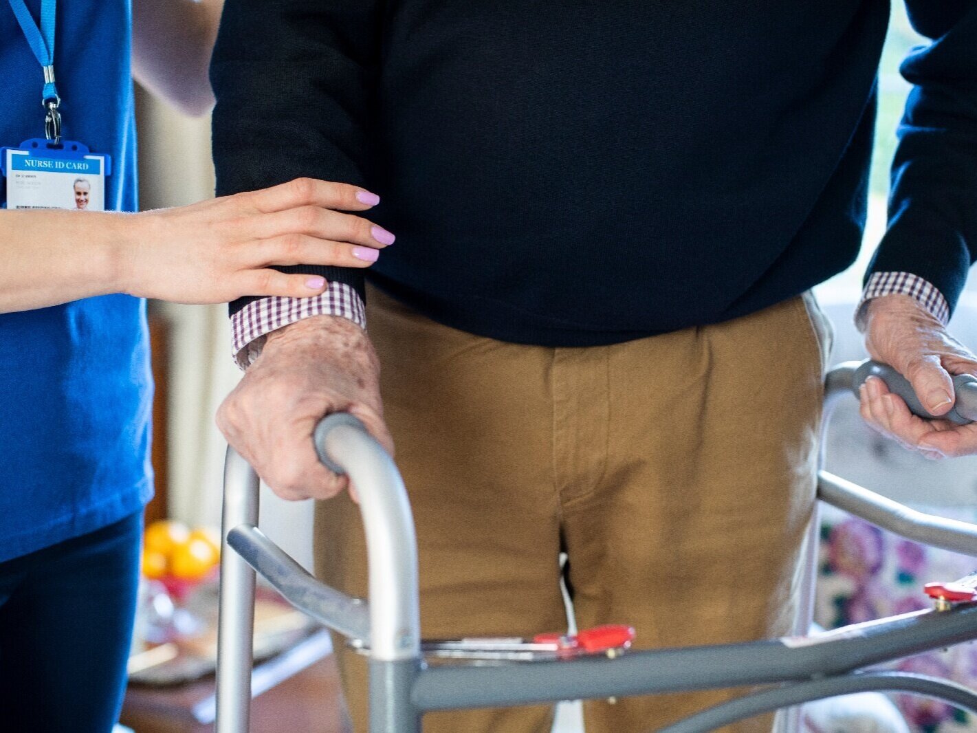 Nurse helping elderly patient use walker
