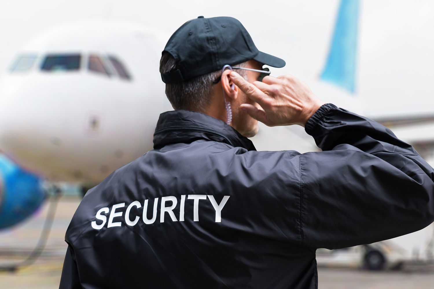 Security guard listening to earpiece against building